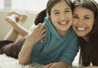 Two people lying on a carpet, smiling and hugging each other closely as they look at the camera, capturing a moment all about love and connection.