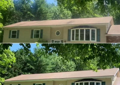 Split-level house with green shutters, shown before and after roof cleaning, surrounded by trees.