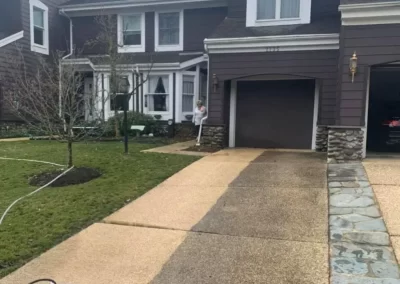 A driveway is partially pressure-washed, showing a clear contrast between clean and dirty sections.